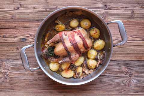 Mit Speck umwickelter Fasan im Bräter mit kleinen Kartoffeln und dunkler Sauce