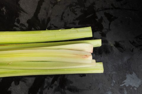 Geschälte, hellgrüne Rhabarberstangen auf dunklem Untergrund