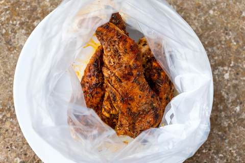 Gegrilltes Fleisch im Gefrierbeutel vor dem Verschließen