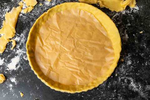 Tarteboden mit Backpapier ausgelegt vor dem Blindbacken