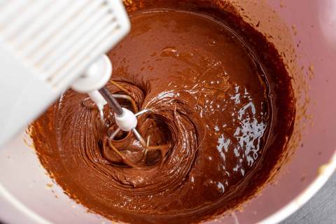 Schokoladenmasse und Eigelb werden mit einem Mixer verrührt