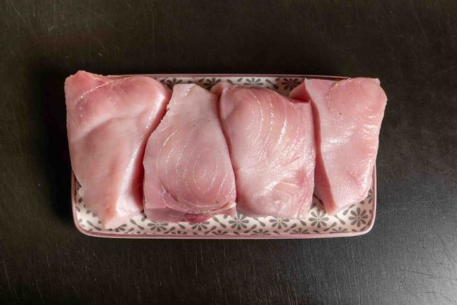 Portionierte Schwertfischstücke auf Teller vor dem Braten oder Grillen